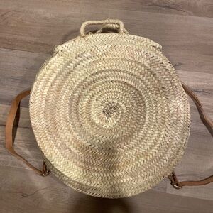 Woven round raffia backpack with adjustable leather straps, handles, zipper top